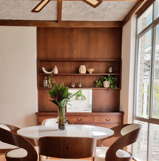  A cozy dining room showcasing warm wooden paneling and a contemporary white dining table.